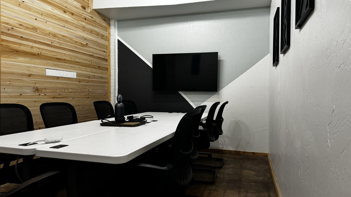 Meeting Room B, a large white conference table with black chairs facing a wall-mounted TV
